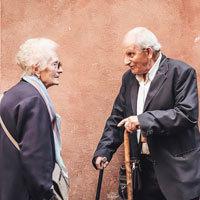 An elderly couple stand and talk.